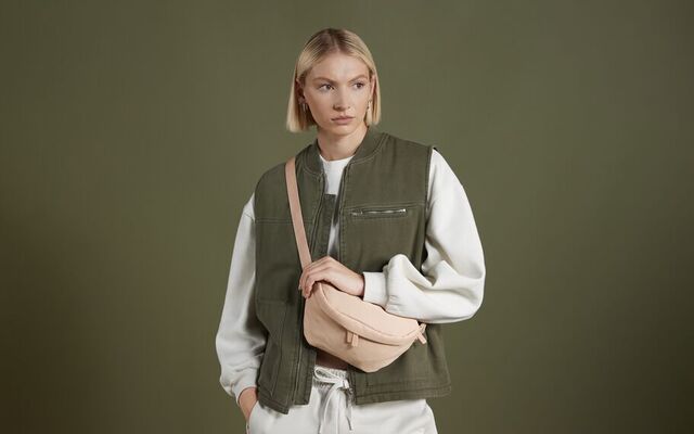 A woman standing with a bagbase cross body bag