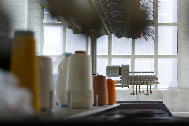 A textile workshop setup with a sewing machine and spools of fabric