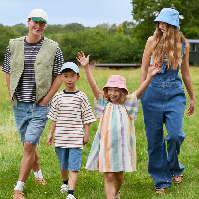 adults and kids walking in a field wearing hats and bucket hats