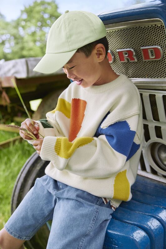 A child on an old tractor wearing a Beechfield cap