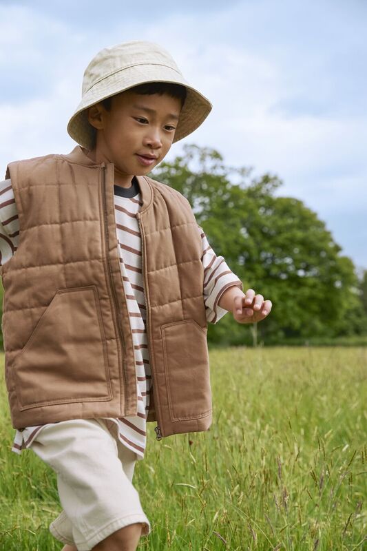 A boy wearing a bucket hat running through a field