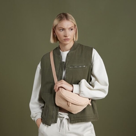 A woman standing with a bagbase cross body bag